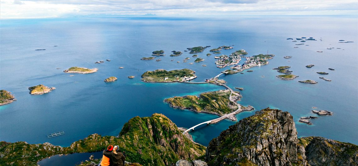 Hikers overlooking Norwegian islands and bridges in Lofoten.