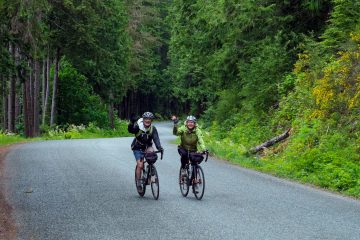 Two happy cyclists biking on British Columbia's "Spirit Loop", following the finest coastal roads and an optional portion of the Vancouver Island Bike.