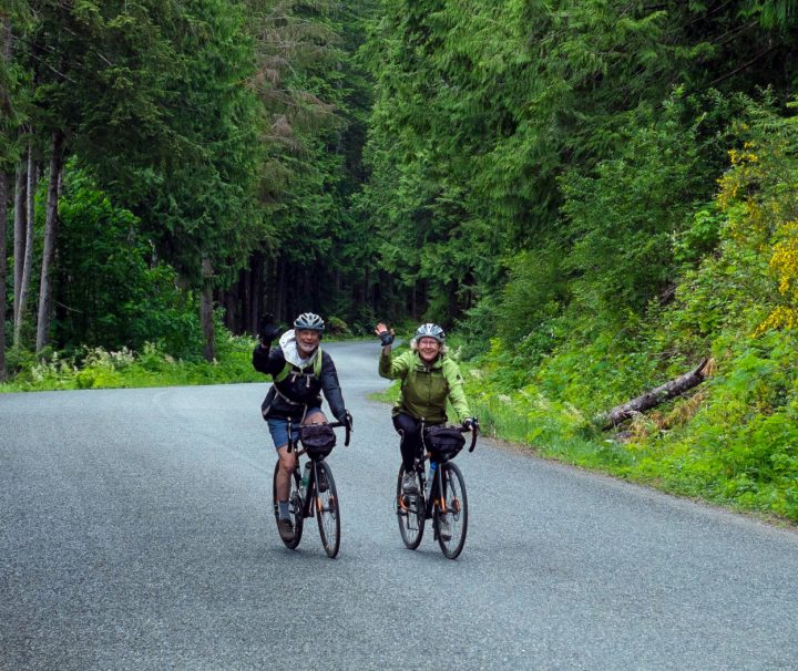 Two happy cyclists biking on British Columbia's "Spirit Loop", following the finest coastal roads and an optional portion of the Vancouver Island Bike.