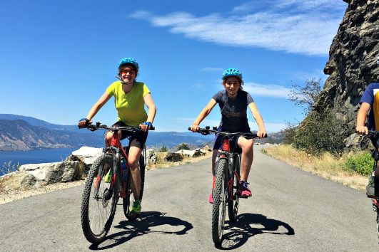 3 happy cyclists on a traffic free cycling path with Freewheeling Adventures in the Okanagan Valley of British Columbia.