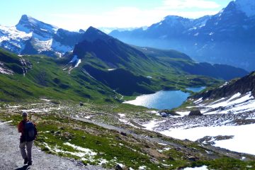 A hiker walking on a spectacular trail though the swiss mountains on a beautiful day on the Switzerland: Bernese Alps Hike with Freewheeling Adventures.