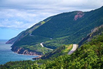 This image captures cyclists riding along the famous Cabot Trail in Cape Breton Highlands National Park, Nova Scotia