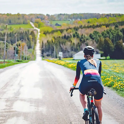This image shows a person cycling on the quiet gravel roads of the Eastern Townships of Quebec