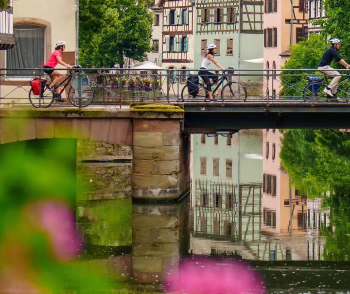 This scene depicts cyclists crossing a bridge in the Petite France district of Strasbourg, France