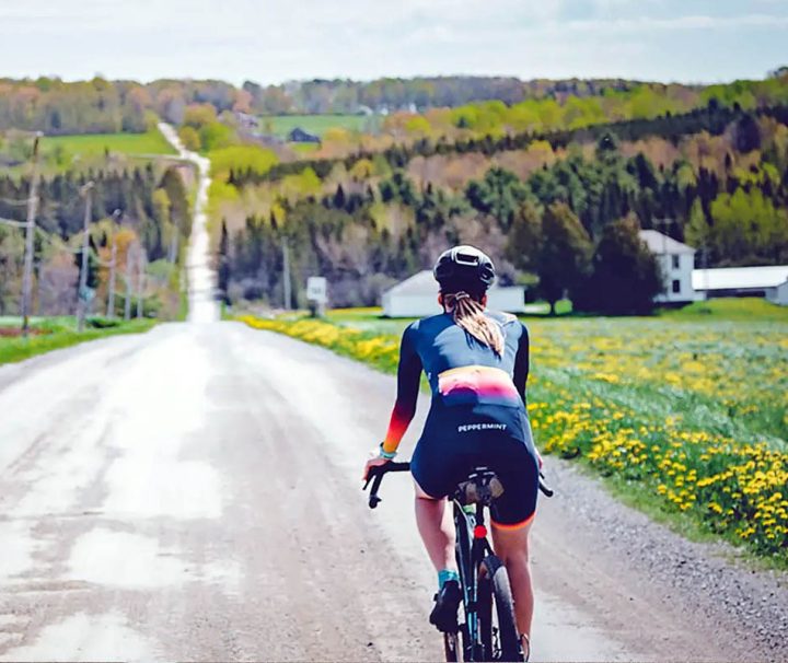 This image shows a person cycling on the quiet gravel roads of the Eastern Townships of Quebec
