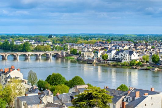 This image depicts a scenic view of the Loire River flowing through the town of Saumur in the Loire Valley region of France