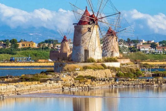 This image shows the historic windmills at the Saline dello Stagnone (Stagnone Salt Pans) near Marsala, Sicily